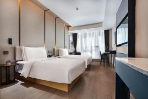 昆明市にあるAtour Hotel Kunming Changshui International Airportのベッド2台とデスクが備わるホテルルームです。
