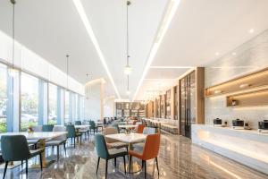 un restaurant avec des tables, des chaises et des fenêtres dans l'établissement Atour Hotel Xiamen Meifeng Binhai Romantic Line, à Tong'an