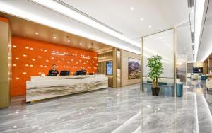 a man sitting at a reception desk in a lobby at Atour Hotel Shenyang South Station Quanyun Road in Shenyang