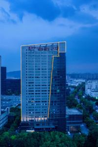 a tall building with lights on it in a city at Atour Hotel Hangzhou Binjiang Powerlong City in Hangzhou