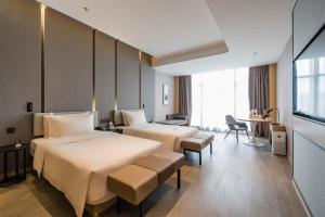 a hotel room with two beds and a desk at Atour Hotel Wuxi Coast City in Wuxi +14 photos