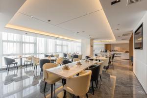a dining room with tables and chairs and windows at Atour Hotel Tianjin Binhai High Speed Railway Station in Binhai