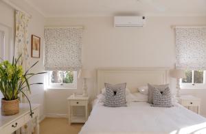 a bedroom with a white bed and two windows at La Belle Vie in Franschhoek