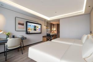 a bedroom with a large white bed and a desk at Atour Hotel Qingdao Tangdao Bay Jinggangshan Station in Huangdao
