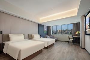 a hotel room with two beds and a desk at Atour X Hotel Xiamen SM Plaza District Government in Xiamen