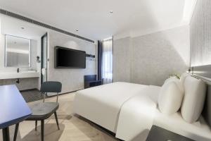 Pokój hotelowy z białym łóżkiem i telewizorem w obiekcie Atour Light Hotel Dalian Xinghai Plaza Shengya Ocean World w mieście Dalian