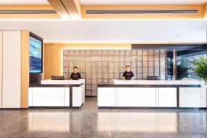 two people sitting at desks in a lobby at Atour Hotel Jinan Shungeng Covention and Exhibition Center Bayi Overpass in Jinan