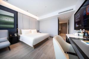 a hotel room with a white bed and a couch at Atour Hotel Qingdao Laoshan Shilaoren Beach in Qingdao