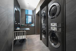 a laundry room with three washing machines and a chair at Atour Light Hotel Changsha IFC Huangxing Road Pedestrian Street in Changsha