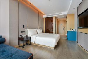 a bedroom with a large white bed and a television at Atour Hotel Kunming Changshui International Airport in Kunming
