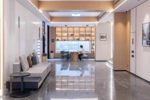 a lobby with a couch and a person sitting at a table at Atour Hotel Jinan Shungeng Covention and Exhibition Center Bayi Overpass in Jinan