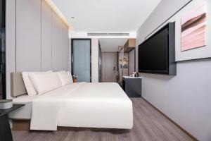 克拉瑪依的住宿－克拉玛依亚朵酒店，卧室配有白色的床和平面电视。