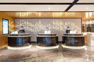 three men sitting at tables in a lobby with laptops at Atour Hotel Xian Bell Tower Yongningli in Xi'an