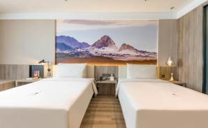 two beds in a room with a painting on the wall at Atour Hotel Xining East Kunlun Road in Xining