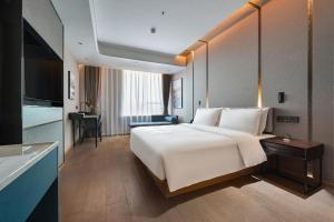 a hotel room with a large white bed and a desk at Atour Hotel Kunming Changshui International Airport in Kunming +11 photos