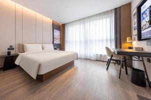 a bedroom with a bed and a desk and a computer at Atour Hotel Jinan Shungeng Covention and Exhibition Center Bayi Overpass in Jinan
