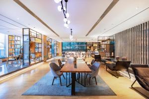 Atour Hotel Yantai South Station Yingchun Street في يانتاى: غرفة طعام مع طاولة وكراسي في مكتبة