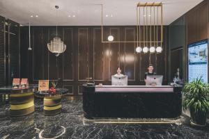 two people sitting at a reception desk in a hotel lobby at Atour Hotel Shanghai Hongqiao International Exhibition Linkong Park in Shanghai