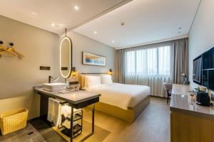 a hotel room with a bed and a sink and a mirror at Atour X Hotel Shanghai Pudong Zhangjiang Park in Shanghai