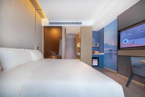 Atour Hotel Wuhan Tiandi Hankou Jiangtan في ووهان: غرفة نوم بسرير كبير وتلفزيون بشاشة مسطحة