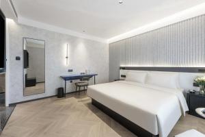 Un dormitorio con una gran cama blanca y una mesa en Atour Light Hotel Dalian Xinghai Plaza Shengya Ocean World en Dalian