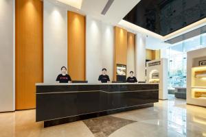 a group of people sitting at a counter in a lobby at Atour X Hotel Xiamen SM Plaza District Government in Xiamen