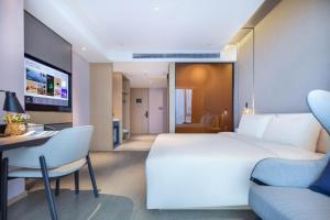 um quarto com uma cama branca, uma secretária e uma cadeira em Atour Hotel Hefei North Square South Station em Hefei