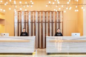 Dos mujeres sentadas en mesas en una habitación con ordenadores portátiles en Atour Hotel Kunming Municipal Government Chunrong Street en Kunming