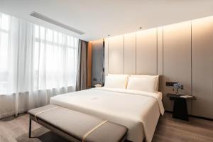 ein Schlafzimmer mit einem großen weißen Bett und einem Fenster in der Unterkunft Atour Hotel Xiamen Gaoqi Airport Chenggong Avenue in Xiamen
