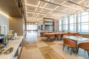 a dining room with tables and chairs and windows at Atour Hotel Wuxi Coast City in Wuxi