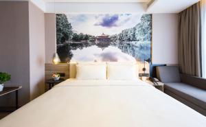 a bedroom with a large bed with a painting on the wall at Atour Hotel Shenyang Olympic Yingpan Street in Shenyang