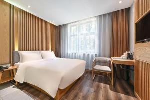 a bedroom with a large white bed and a desk at Atour X Hotel Beijing Sanlitun Agricultural Exhibition Hall in Beijing