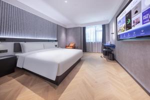 a bedroom with a white bed and a flat screen tv at Atour Light Hotel Fuzhou Sanfang Qixiang in Fuzhou