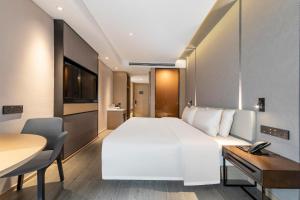 um quarto de hotel com uma grande cama branca e uma secretária em Atour Hotel Shaoxing Heqiao em Shaoxing