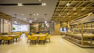 a restaurant with yellow chairs and tables and a cafeteria at Atour Hotel Hangzhou Xiaoshan Peoples Square in Hangzhou