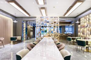 Atour X Hotel Hangzhou Binjiang Jiangnan Avenue في هانغتشو: طاولة طويلة في غرفة مع كراسي وطاولات
