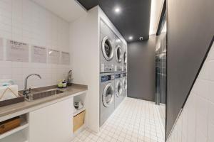 a laundry room with three washing machines and a sink at Atour Hotel Shanghai Pudong Airport Chuansha Station in Shanghai