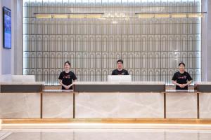 three men standing behind a desk in a room at Atour X Hotel Shenzhen Guanlan Shanshui Pastoral in Lung Wa