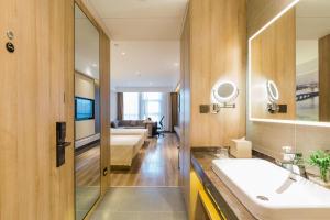 ein Badezimmer mit einem Waschbecken und ein Wohnzimmer in der Unterkunft Atour Hotel Hefei South Station Binhu Convention and Exhibition Center in Hefei