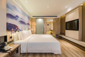 ein Hotelzimmer mit einem großen Bett und einem Flachbild-TV in der Unterkunft Atour Hotel Hefei South Station Binhu Convention and Exhibition Center in Hefei