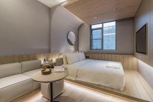 um quarto de hotel com uma cama e um sofá em Atour Hotel Shanghai World Expo Center em Xangai