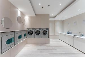 a laundry room with three washing machines and a sink at Atour Light Hotel Shanghai Xujiahui Jiaotong University in Shanghai
