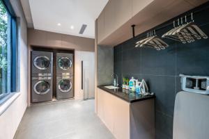 a laundry room with three washing machines and a sink at Atour Light Hotel Guangzhou Panyu Hanxi Changlong in Guangzhou