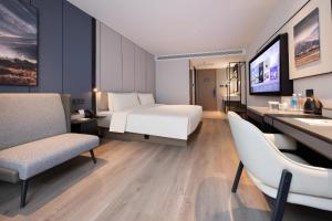 a hotel room with a bed and a desk and chairs at Atour Hotel Nanjing Jinma Road Station in Nanjing