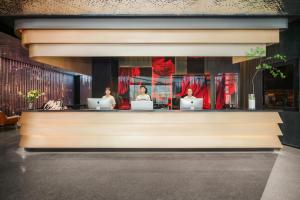 three people working on their laptops in a lobby at Atour Hotel Chengdu Jinniu Southwest Jiaotong University in Chengdu