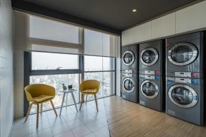 a laundry room with four washing machines and two chairs at Atour Hotel Handan New Century in Handan