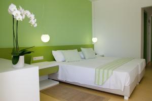 - une chambre avec un lit blanc et un vase de fleurs dans l'établissement Palm Beach Hotel, à Stalida