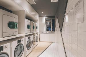 a white laundry room with washing machines and a sink at Atour S Hotel Shanghai Xujiahui Tianyaoqiao in Shanghai