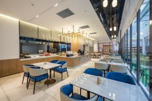 a restaurant with tables and chairs and a kitchen at Atour Hotel Shanghai Huajing in Shanghai