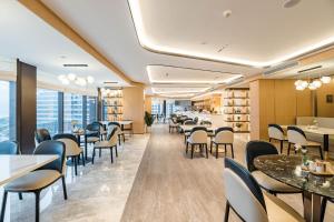 ein Esszimmer mit Tischen und Stühlen und Fenstern in der Unterkunft Atour Hotel Tonglu Fuchunjiang in Tonglu